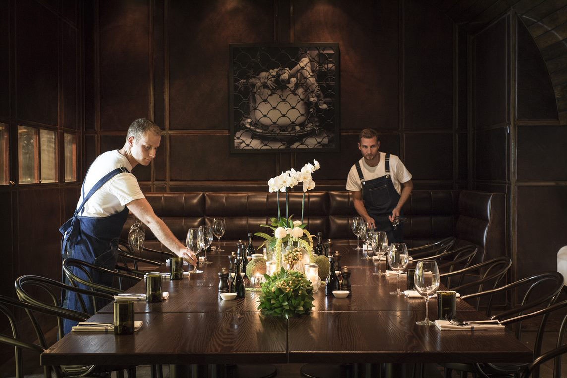 Two waiters putting wine glasses on a table